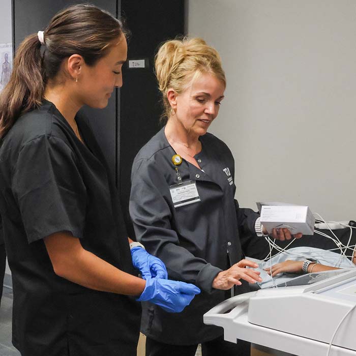 ekg student and instructor using an ekg machine